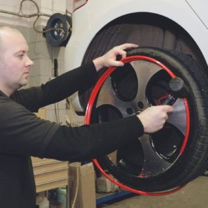 Man fitting a set of Red AlloyGator alloy wheel protectors and Tyre Protectors to a White Volkswagen Car