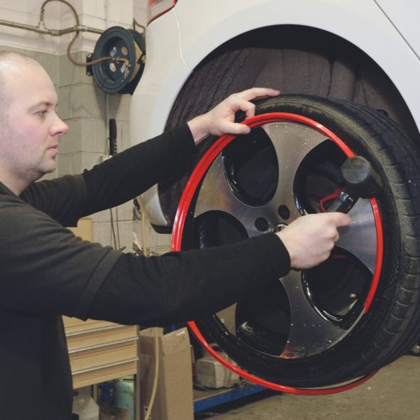 Man fitting a set of Red AlloyGator alloy wheel protectors and Tyre Protectors to a White Volkswagen Car